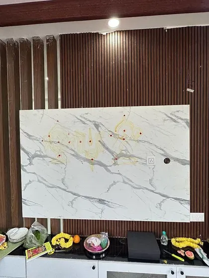 A work-in-progress shot of a TV unit installation. The combination of a marble-finish panel and fluted wood accents demonstrates our approach to mixing materials for a contemporary and textured look.
