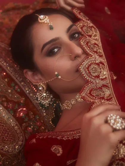 A stunning close-up of a traditional bridal look, with a beautiful nath and a soft, smokey eye peeking through the dupatta.