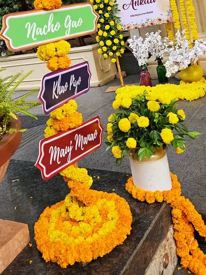 Fun and festive signage for a Haldi ceremony, encouraging guests to eat, drink, and be merry. The signs are decorated with bright marigold flowers, tying them into the overall traditional theme.