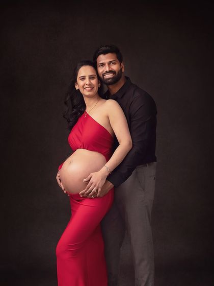 A strong and beautiful pose showcasing the baby bump. The partner's embrace from behind adds a sense of support and unity.