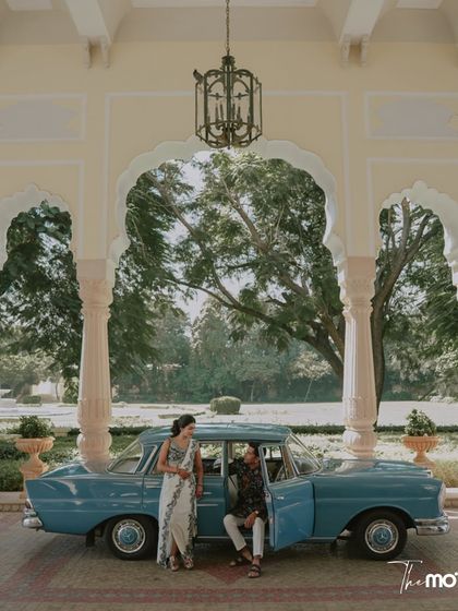 A vintage-inspired portrait from a welcome lunch in Rajasthan. The couple poses with a classic car at the Rambagh Palace, creating a scene filled with heritage and charm.