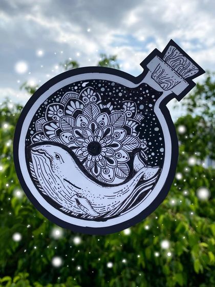 A magical piece featuring a whale and a floral mandala inside a bottle. This black and white ink illustration was cut out and photographed against a natural background to enhance its enchanting feel.