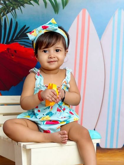 A sweet portrait of our little beach babe. The colorful, tropical backdrop and her cute outfit create a perfect summer vibe.