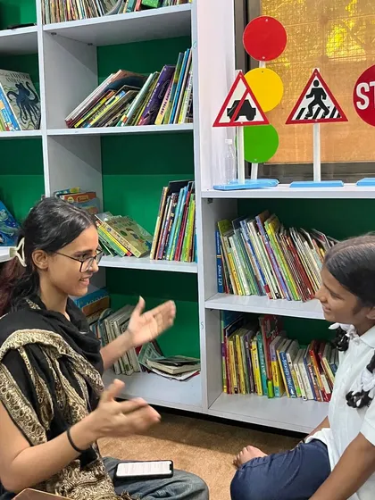 A research assistant engages with a student in our library, surrounded by books and learning materials. These pre-tests set a baseline to measure the progress and joy that stories bring into children's lives.