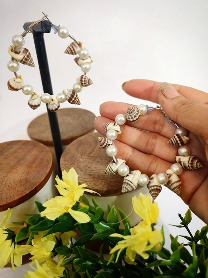 A close-up of the latest seashells and pearl designer hoop earrings, perfect for summer.