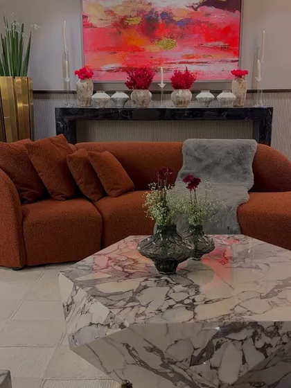 A beautifully styled living room, where our floral arrangements complement the client's bold taste in furniture and art. The red and orange tones are carried from the sofa to the flowers.