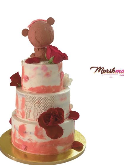 The back view of the 3-tier teddy bear cake, showing the continuation of the watercolour buttercream effect and the placement of fresh red roses.
