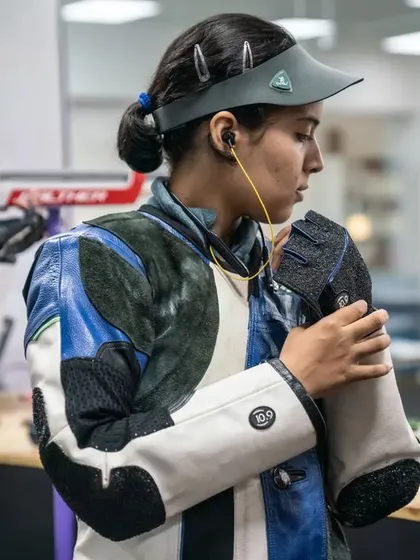 A moment of preparation between shots. An athlete adjusts her gear, demonstrating the meticulous attention to detail that competitive shooting demands.