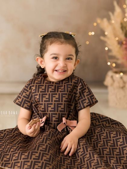 A bright and happy portrait of a young girl seated on a fluffy rug. Her genuine smile lights up the entire photograph.