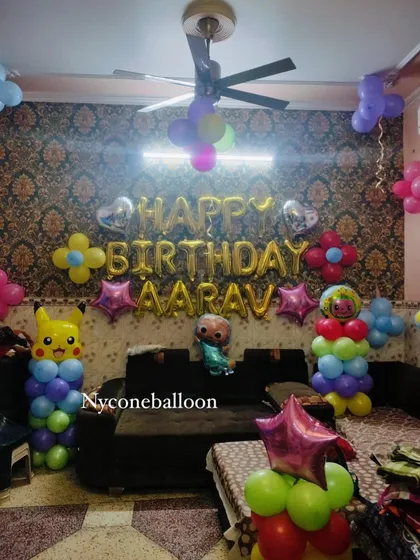 A fun mashup theme for Aarav's birthday, featuring both Cocomelon and Pikachu. The living room is filled with colorful balloon columns topped with character foils and a golden 'Happy Birthday' balloon banner.