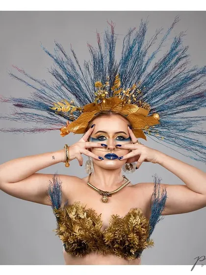 A wider shot of the avant-garde headpiece, revealing the full construction of feathers and golden leaves.