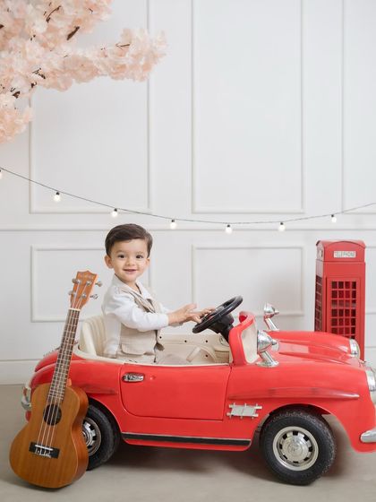 Adding a musical touch to his birthday shoot, this little one sits in his red car with a ukulele, ready for a birthday jam session.