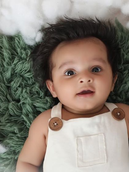 Look at that full head of hair and those bright, curious eyes. This three-month-old baby boy is resting on a bed of fluffy clouds, a simple and dreamy setup that keeps the focus on him.