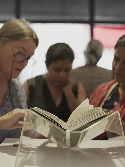 Visitors at the "Mindscapes" exhibition engaging with the 'Directory of the Outsiders' book, reading the stories and sharing in a moment of collective reflection.