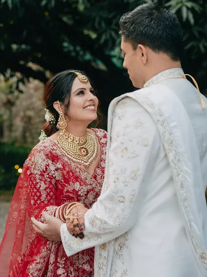 A beautiful close-up of the bride looking lovingly at her groom. Her radiant smile and the intricate details of her jewelry are perfectly captured in the soft, natural light of their outdoor wedding.