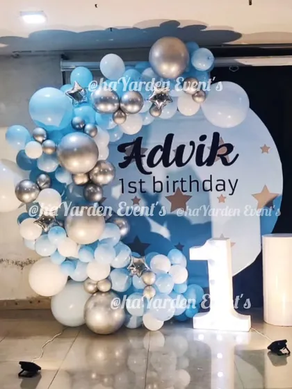 Another beautiful first birthday setup with a blue and silver balloon arrangement on a custom 'Advik's 1st birthday' backdrop.