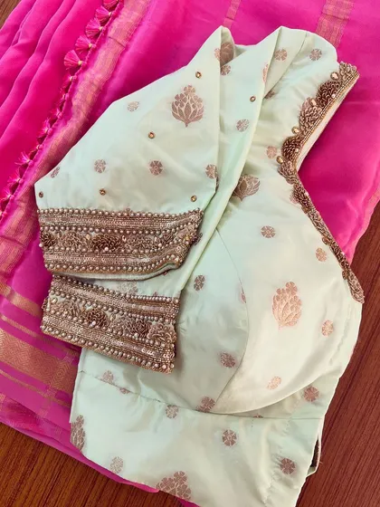 A beautiful contrast pairing of a pink KSIC Mysore silk saree with a custom-designed mint green blouse featuring heavy zardosi work on the cuffs.