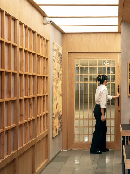 The corridor at Seoul, featuring wooden lattice walls and a backlit ceiling membrane. This design choice transforms a potentially narrow passage into an expansive and welcoming journey, setting the tone for the dining experience ahead.