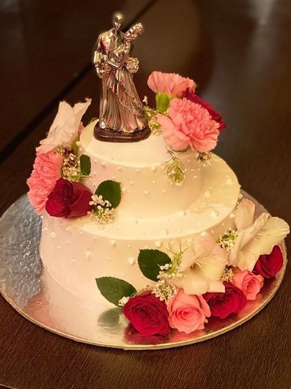 A classic two-tier anniversary cake with fresh flowers and a couple topper.