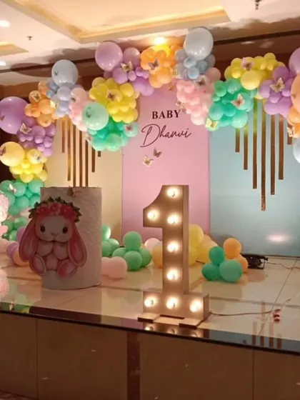 A sweet bunny-themed first birthday party, using pastel balloons and a large light-up number '1' to create a soft and adorable setting.