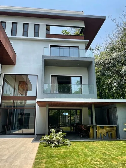A daytime view of the Koramangala residence, showing the clean lines and material palette. The design incorporates large glass panels and balconies to maximize natural light and offer views of the surrounding greenery.