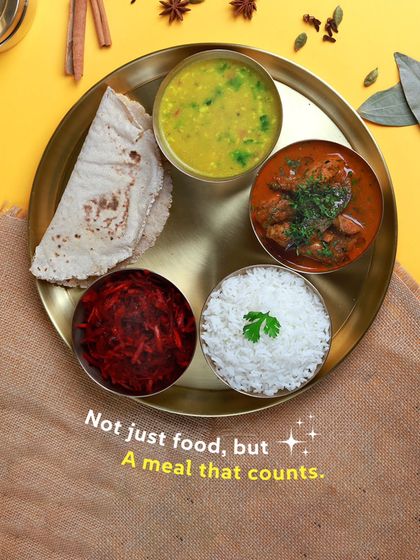 A meal that counts. This non-veg thali is carefully portioned to be satisfying but not heavy, featuring chicken curry, dal, rice, salad, and roti.