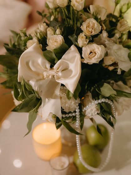 A beautiful centerpiece featuring a large satin bow nestled among white roses and greenery.