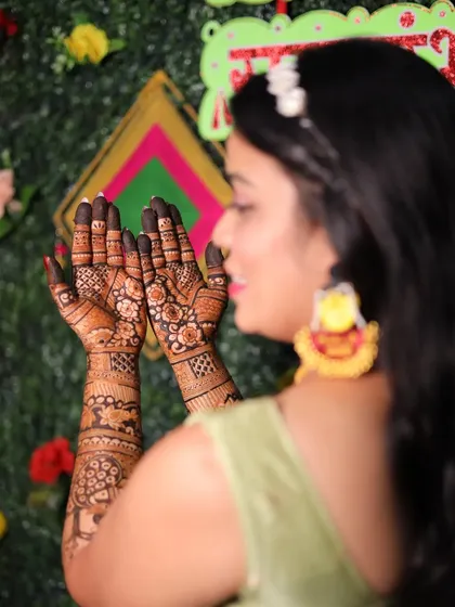 A candid shot of a guest showing her mehendi during the ceremony. The design is focused on the palms with a beautiful floral pattern.