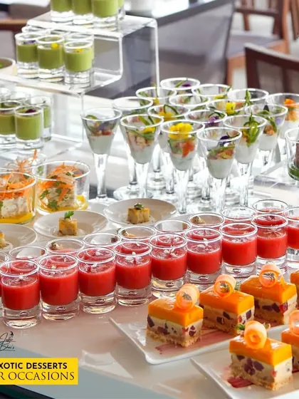 Savor our exotic desserts at your occasions. This beautiful display features a variety of single-serving desserts, including fruit mousses and layered cakes in shot glasses, offering a delightful and elegant end to the meal.