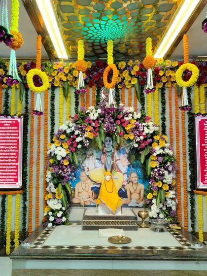 This decoration for the Sai Baba Mandir features hanging floral elements and traditional marigold garlands. The design adds color and festivity to the temple's interior, enhancing the worship experience.