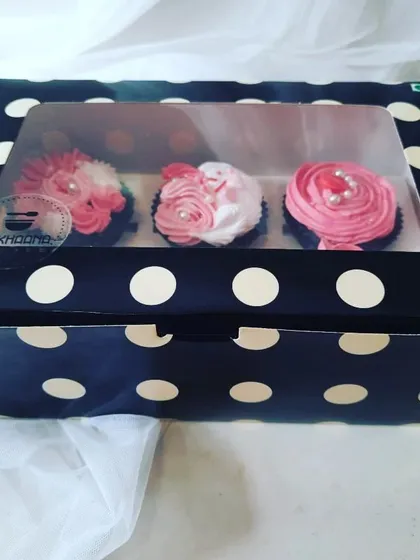 A beautiful gift-ready box of three of our signature frosted cupcakes, seen through a clear window. This is how our treats arrive, packed securely and with care, straight from a local home baker's kitchen to you.