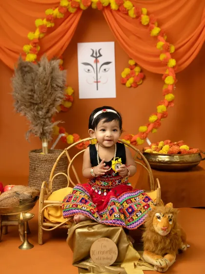 A sweet smile from our little goddess. The Dussehra setup includes marigold garlands, a miniature throne, and symbolic artwork to create an authentic festive feel.