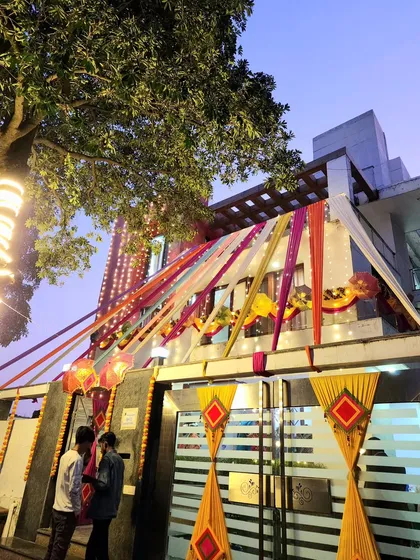 A full view of a decorated wedding house at dusk, with colourful fabric drapes and lighting creating a festive and welcoming atmosphere.