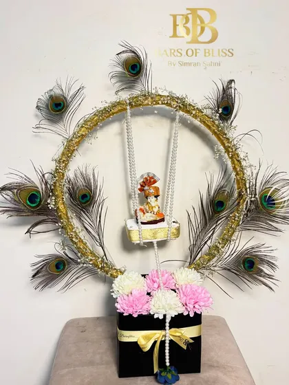 A classic version of my Janmashtami Jhula hamper, with a golden ring adorned with peacock feathers and a floral base.