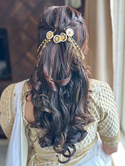 A modern take on traditional hair accessories. This half-up style with soft curls is enhanced by a unique golden hairpiece.