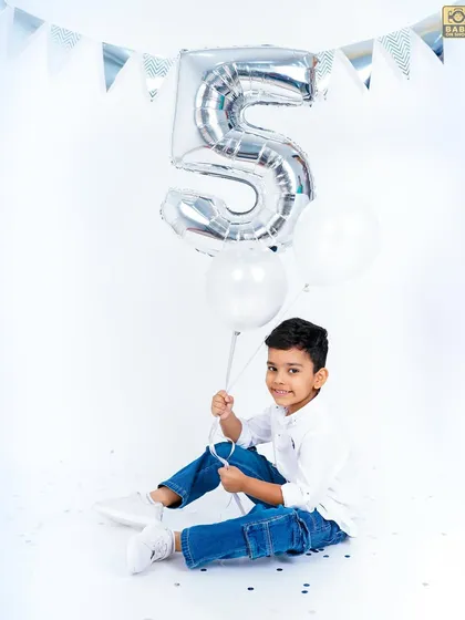 A classic birthday shot with a number five balloon. The simple white background keeps the focus entirely on the child.