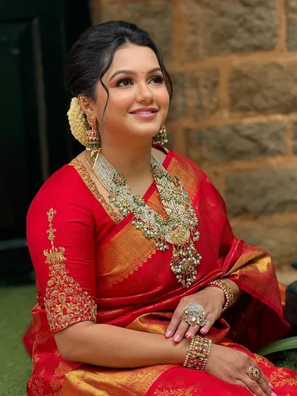 A portrait of a client in her red silk saree and custom embroidered blouse. The elbow-length sleeves with detailed embroidery are a classic and elegant choice.