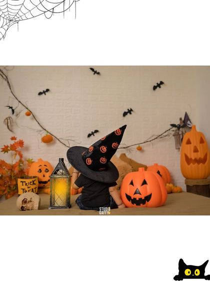 A spooky and fun Halloween setup with a baby dressed as a little witch among pumpkins and bats.