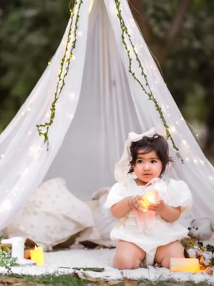 We can take the magic outdoors. This dreamy pre-birthday session features a beautiful tent and fairy light setup in a Delhi NCR garden, creating a truly enchanting memory.