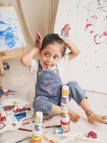 A silly and fun moment with paint on her hands, this little girl is having a wonderful time during her artist-themed shoot.