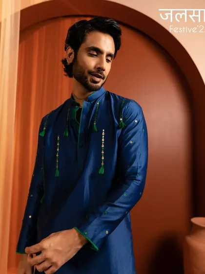 This shot highlights a natural and fresh grooming look. The skin is perfected to look healthy and even, complementing the vibrant blue of the festive kurta.