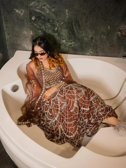 A creative and edgy shot, sitting in a bathtub in a heavily embroidered brown lehenga. This shows I can create unconventional and memorable content.