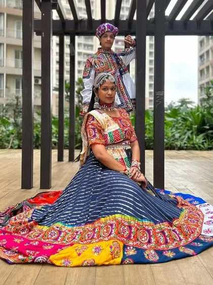 A power pose from a stylish couple. Her multi-colored lehenga with its wide flair and his matching embroidered Kedia and pagdi create a stunning visual. Perfect for making a grand entrance.