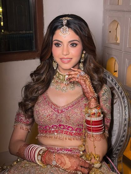 A close-up showcasing the flawless skin and detailed eye makeup. The henna on her hands adds to the richness of the overall bridal look.