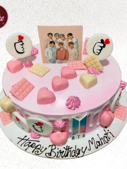 Another great cake for a BTS fan. This pink drip cake is loaded with pink and white chocolates, hearts, and a photo of the band.