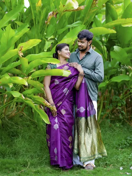 Surrounded by lush greenery, the couple shares a romantic look. The rich purple of the bride's saree stands out beautifully.
