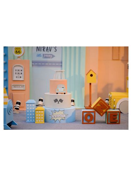A detailed shot of the cake area for our vehicle theme, featuring a custom cake, 'ONE' blocks, and miniature city building props.