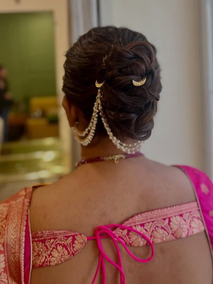 A close-up view of the braided bun with moon and pearl accessories. The details show the clean lines and careful placement that make this hairstyle so special and elegant.