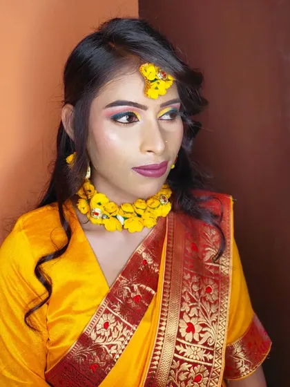 A vibrant Haldi makeup look. The eyes are colorful with yellow and blue, and the jewelry is made of fresh yellow flowers.