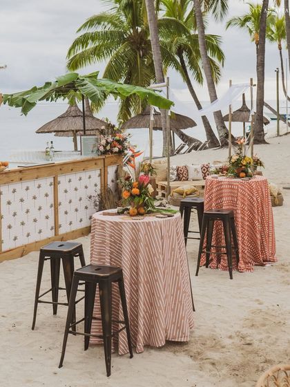 Cocktail tables with patterned linens provide spots for guests to stand and mingle by the beach bar.